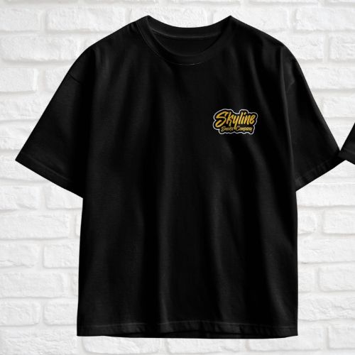 Black t-shirt with yellow logo on a white brick wall background